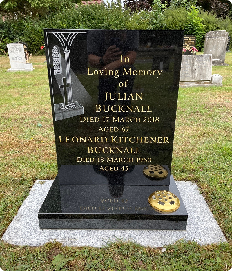 Black gravestone with gold inscriptions in cemetery.
