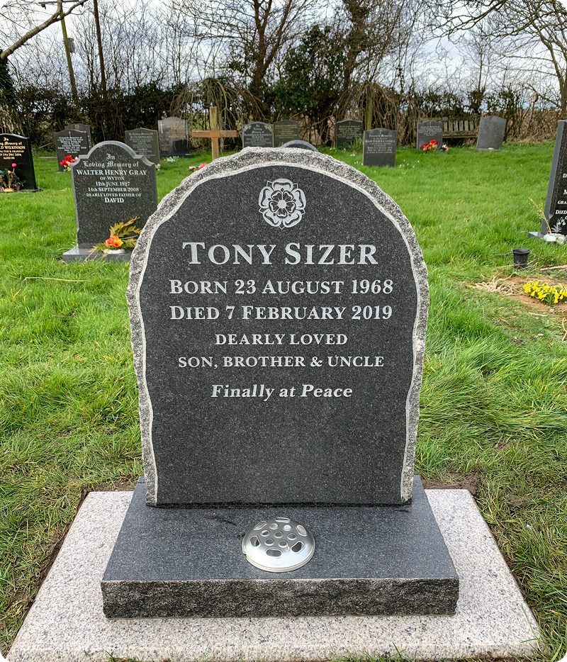 Headstone in a green cemetery setting.
