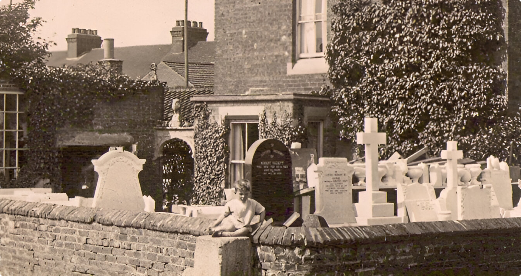 Person sitting by gravestones outside building.